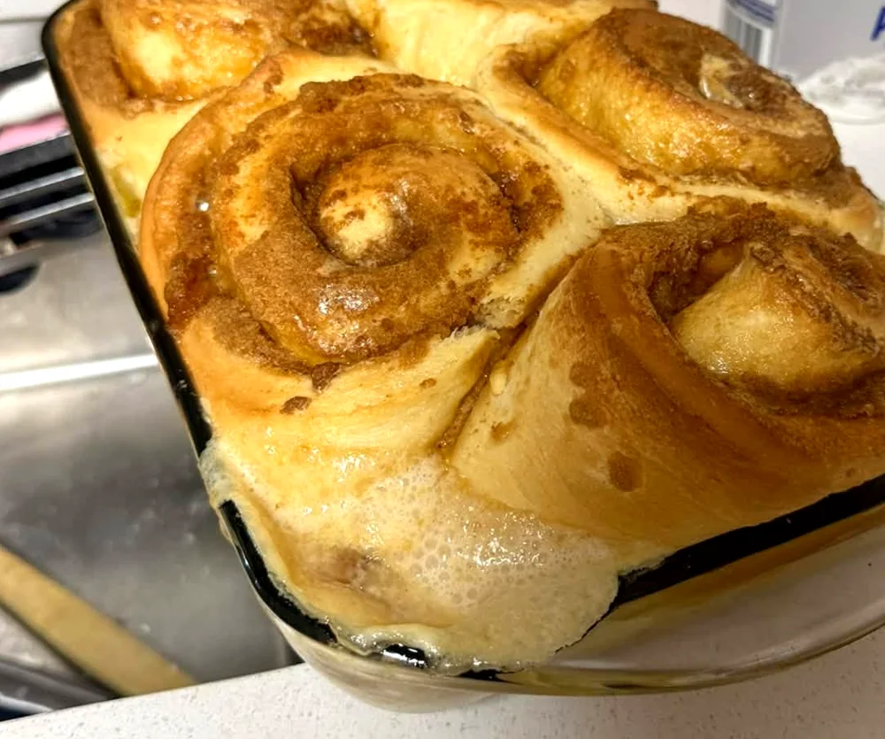 A pan of fresh baked cinnamon rolls with caramelized brown sugar tops